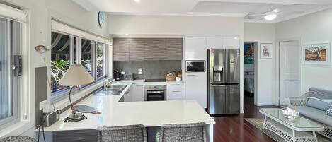 A modern kitchen with a central island, stainless steel appliances, and a dining area with wicker chairs.