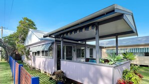 Una casa con portico coperto, giardino recintato e un'area giardino.