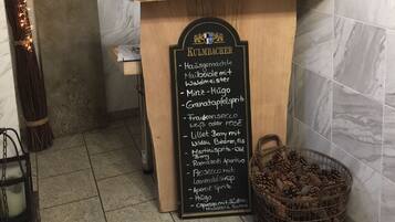 A hotel reception area with a wooden counter, a blackboard menu, and a decorative wreath.