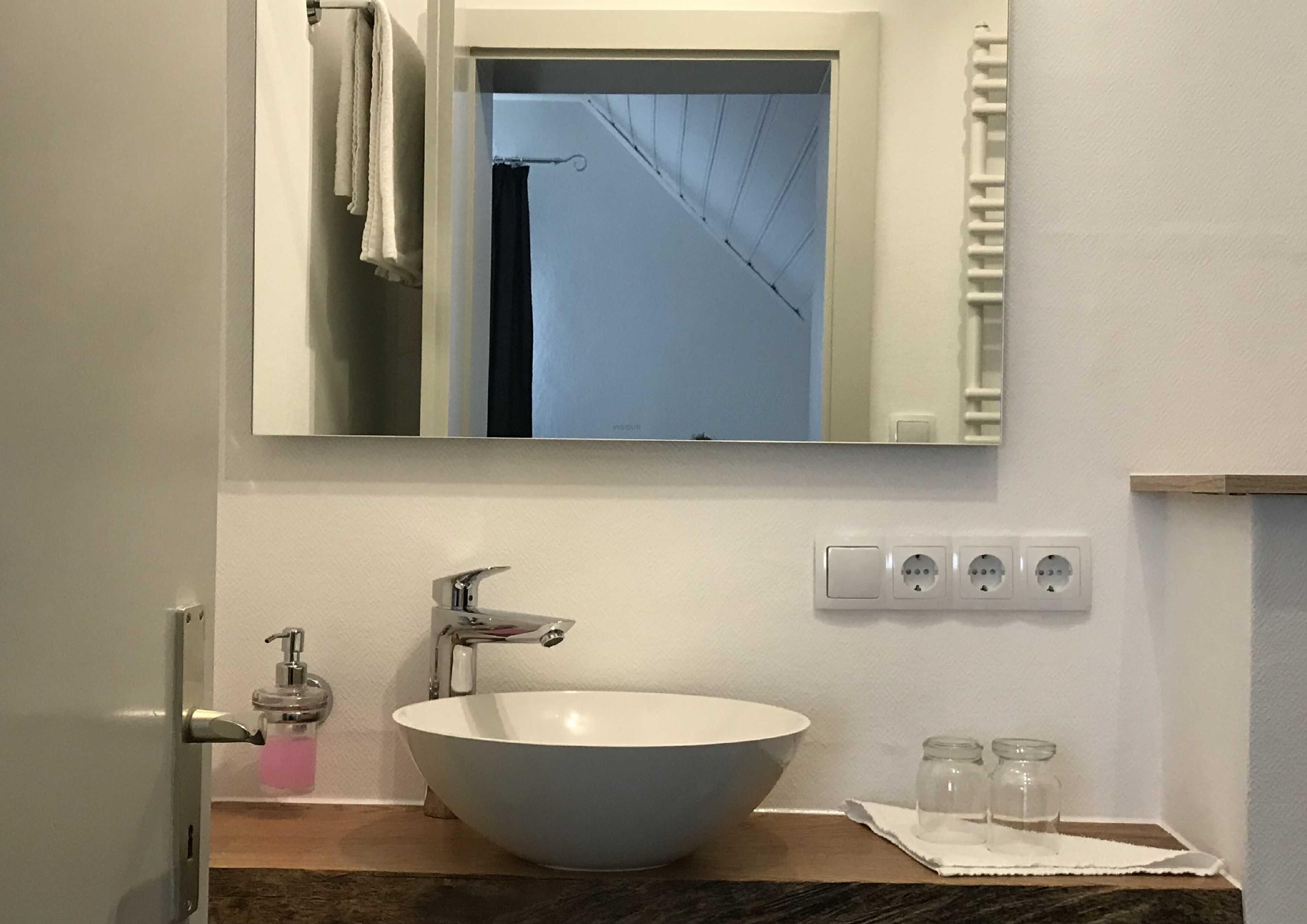 A bathroom with a white sink, a mirror, and a towel rack.