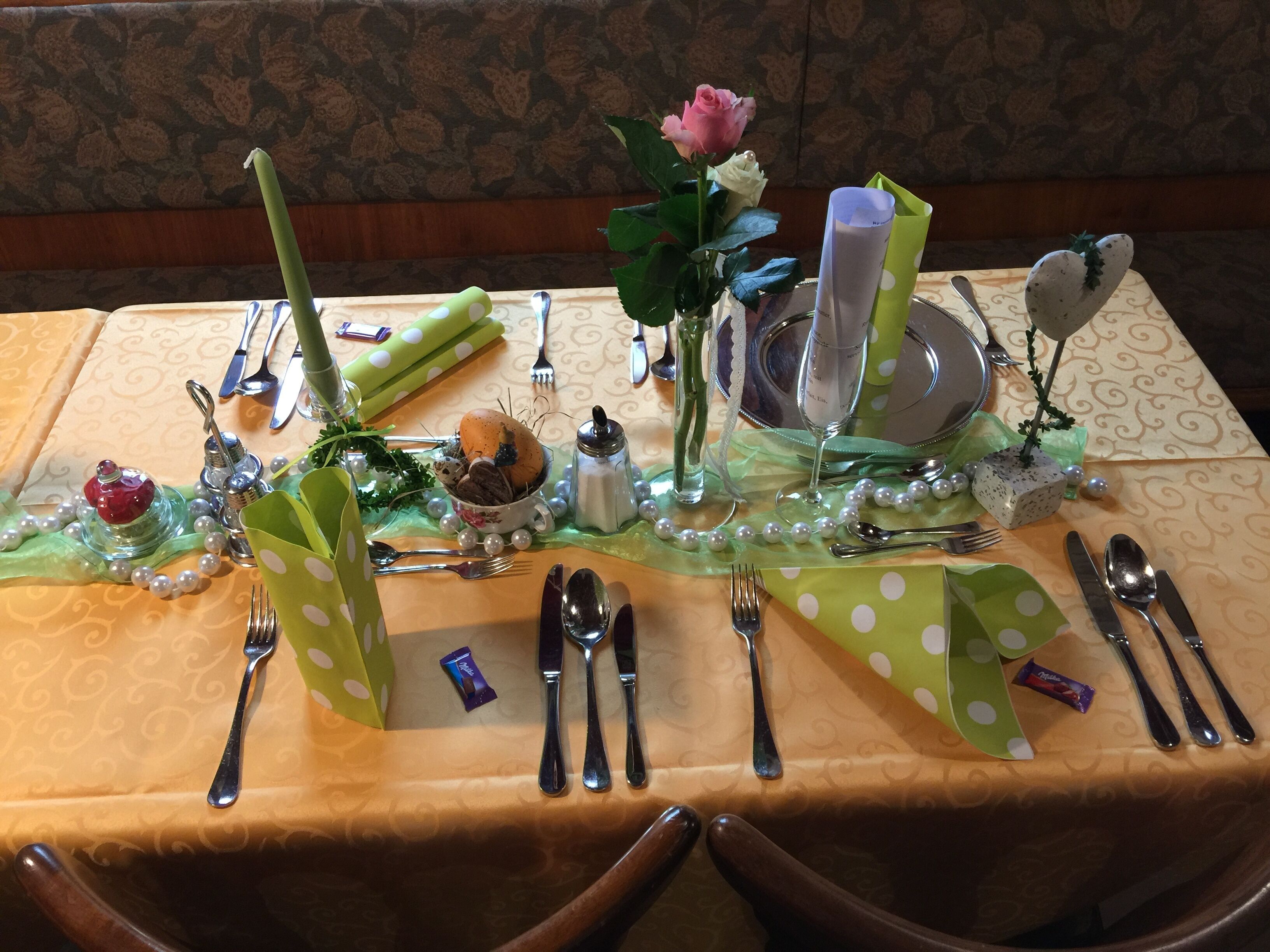 A table set with silverware, a vase with a rose, and decorative elements.