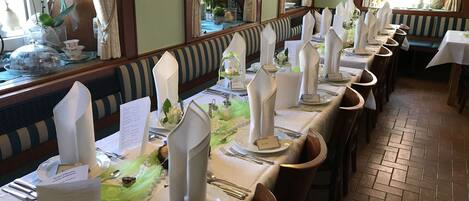 A long dining table with white napkins, name cards, and silverware.