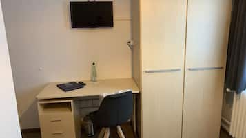Ein kleiner, kompakter Raum mit Schreibtisch, Stuhl und Kleiderschrank.