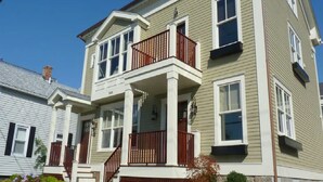 Une maison à deux étages avec un balcon, un porche à l’avant et une cheminée.