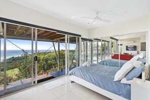 Une chambre moderne dotée d’un grand lit, d’une télévision et d’un balcon offrant une vue panoramique.