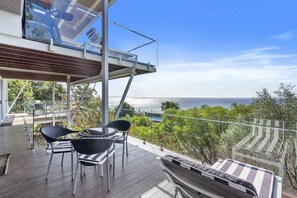 Un balcon donnant sur l’océan, aménagé avec des chaises et une table.