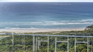 Paesaggio costiero con spiaggia, oceano e vegetazione lussureggiante.