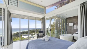 Una camera da letto moderna con un ampio letto, un angolo relax e vista sull'oceano.