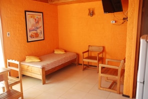 A small room with a single bed, a wooden chair, and a table. - Cabañas Diquen's El Tabo (El Tabo)