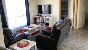 Un salon avec un canapé, une table basse, un téléviseur et une bibliothèque.