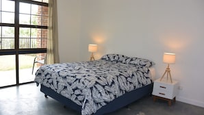 Een slaapkamer met een bed, twee nachtkastjes en een raam.