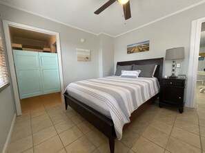 A bedroom with a bed, a nightstand, a ceiling fan, a door leading to a closet, and a wall-mounted picture. - Breaking Away 1br/1ba + Sleeper, 2nd fl Ocean Peek (Isle of Palms)