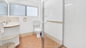 A modern bathroom with a glass shower enclosure, a toilet, a sink with a mirror above, and a window. - Two bedroom unit in central location and only minutes walk to Deadmans... (Point Lookout)