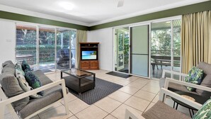 A spacious living area with a television, sliding glass doors, and a ceiling fan. - Two bedroom unit in central location and only minutes walk to Deadmans... (Point Lookout)