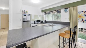 A modern kitchen with a granite countertop, stainless steel appliances, and a window with a view of greenery. - Two bedroom unit in central location and only minutes walk to Deadmans... (Point Lookout)