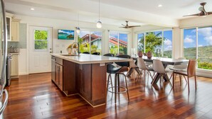 Uma cozinha moderna com uma ilha grande, banquetas de bar e uma área de refeições com vista para a paisagem.