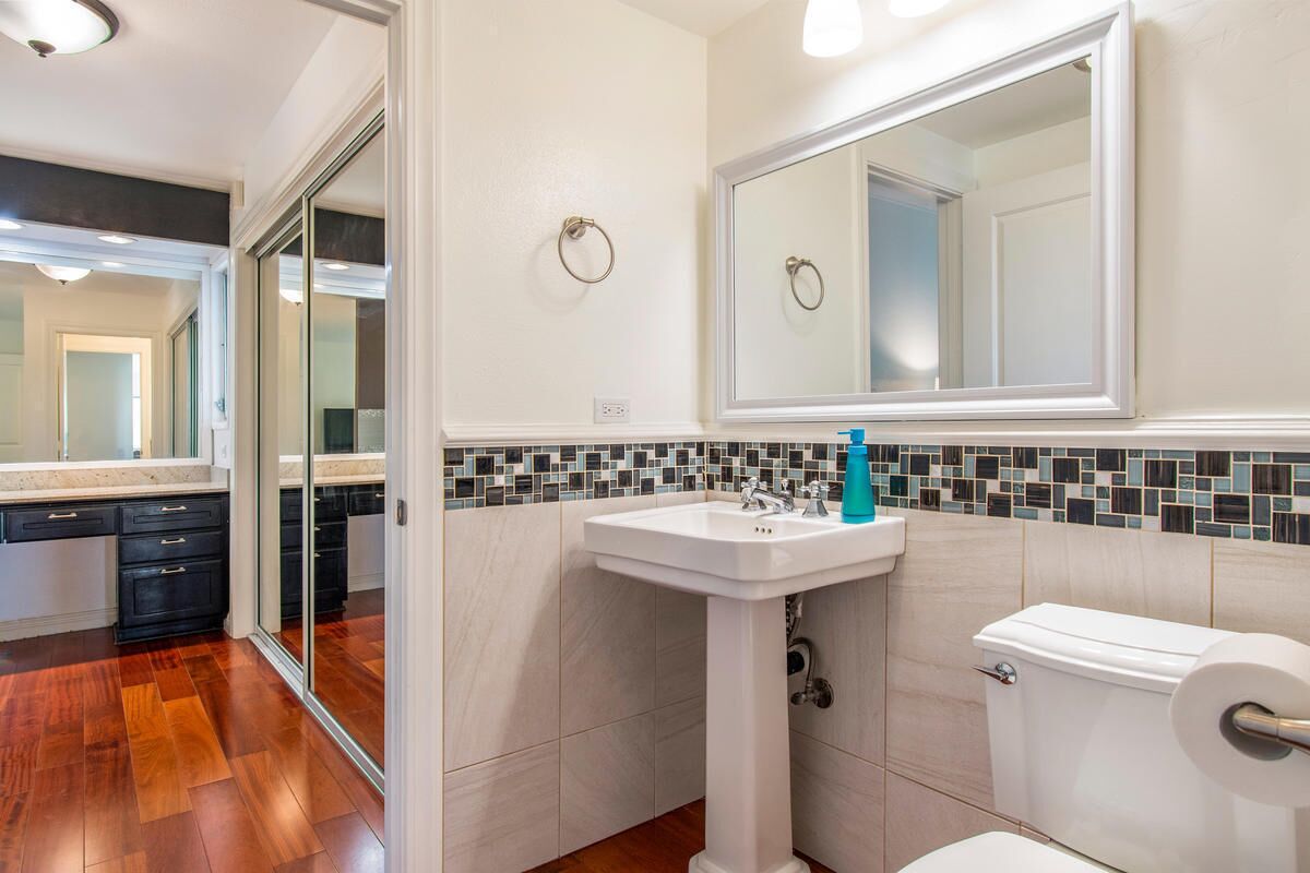 A bathroom with a white sink, a toilet, and a mirror.