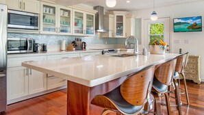 Uma cozinha moderna com uma ilha grande, eletrodomésticos de aço inoxidável e banquetas.