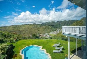 A swimming pool with a view of a town and mountains in the background.