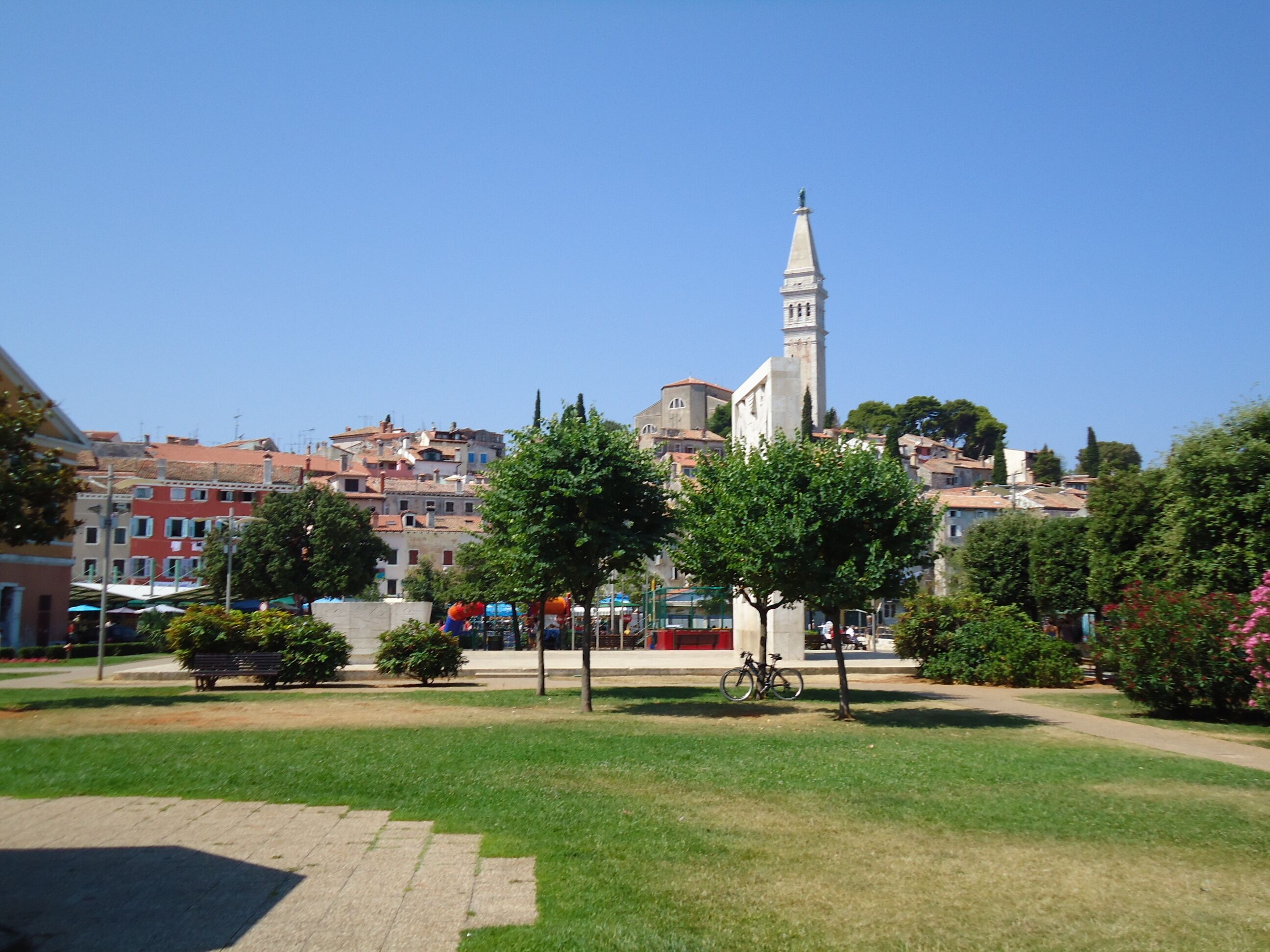 Un parc doté d’un monument central, entouré de pelouses verdoyantes et d’arbres.