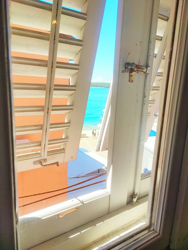 Una finestra con vista su una spiaggia e un edificio dalle pareti arancioni e bianche.