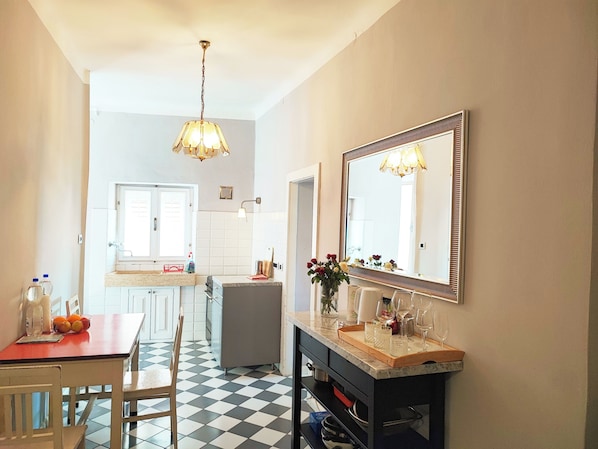 Una cocina moderna con piso a cuadros, una zona de comedor con mesa y sillas, y un espejo grande sobre la encimera.