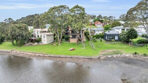 A residential area with houses, a grassy lawn, and a body of water. - Coolabah Court - Merimbula (Merimbula)