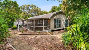 A house with a covered porch, surrounded by trees and a garden. - 7 Belle Court - Rainbow Shores. Huge Beach House! Pets Welcome. Property not fenced. Ducted aircon (RAINBOW BEACH)