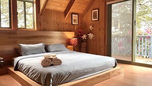 Una stanza in legno con un letto, una finestra e una porta.
