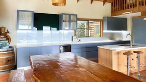 Una cucina moderna con soffitto in legno, un'isola grande, sgabelli da bar e una finestra che si affaccia sull'esterno.