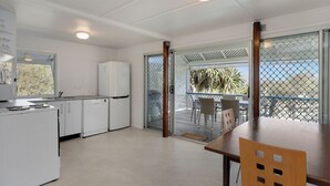 Een keuken met witte kastjes, een koelkast, en een eethoek met een tafel en stoelen.