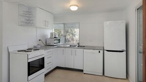 Een moderne keuken met witte kasten, een ingebouwde oven, een magnetron, een vaatwasser en een koelkast.