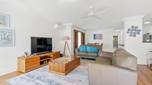 Una sala de estar moderna con un televisor de pantalla plana, un mueble bajo de madera y un sofá color beige.