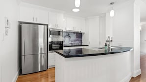 Una cocina moderna con armarios blancos, electrodomésticos de acero inoxidable y una isla con encimera negra.