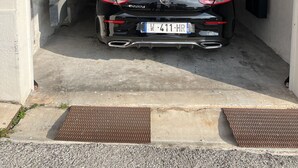 Une voiture noire est garée à l’intérieur d’un garage, et sa plaque d’immatriculation est visible.
