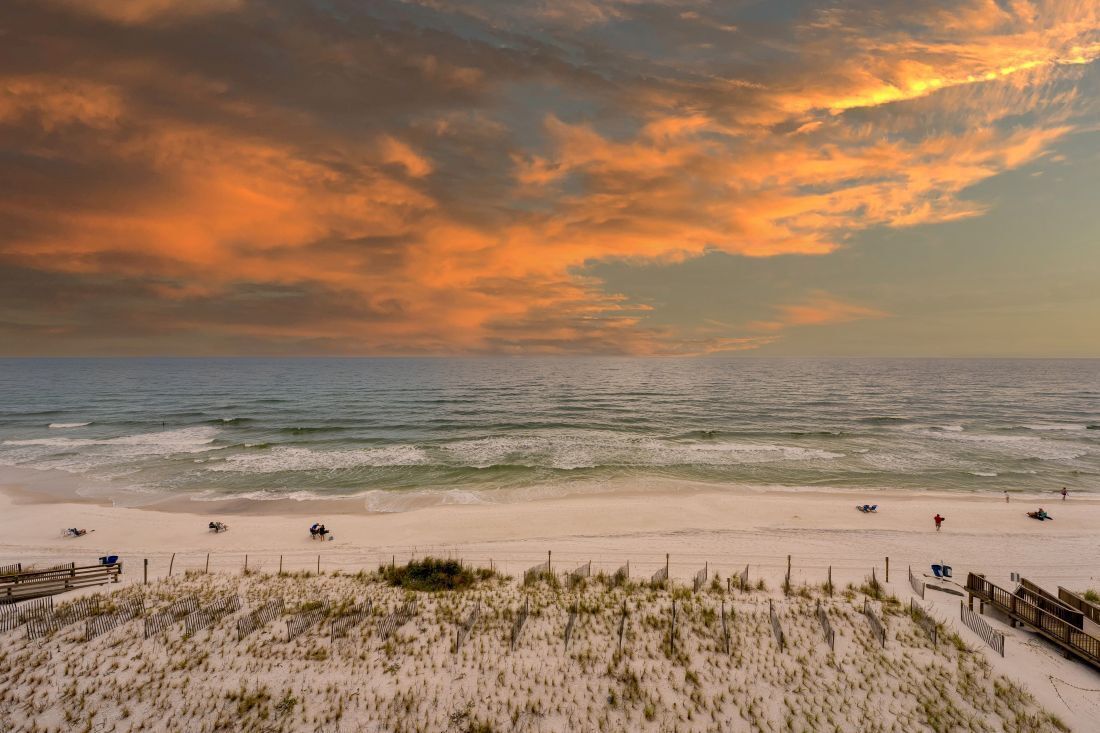 A beach with a wooden boardwalk and dunes.