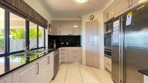A modern kitchen with white cabinets, a stainless steel refrigerator, and a black countertop. - Seahaven - Located in Toogoom (TOOGOOM)