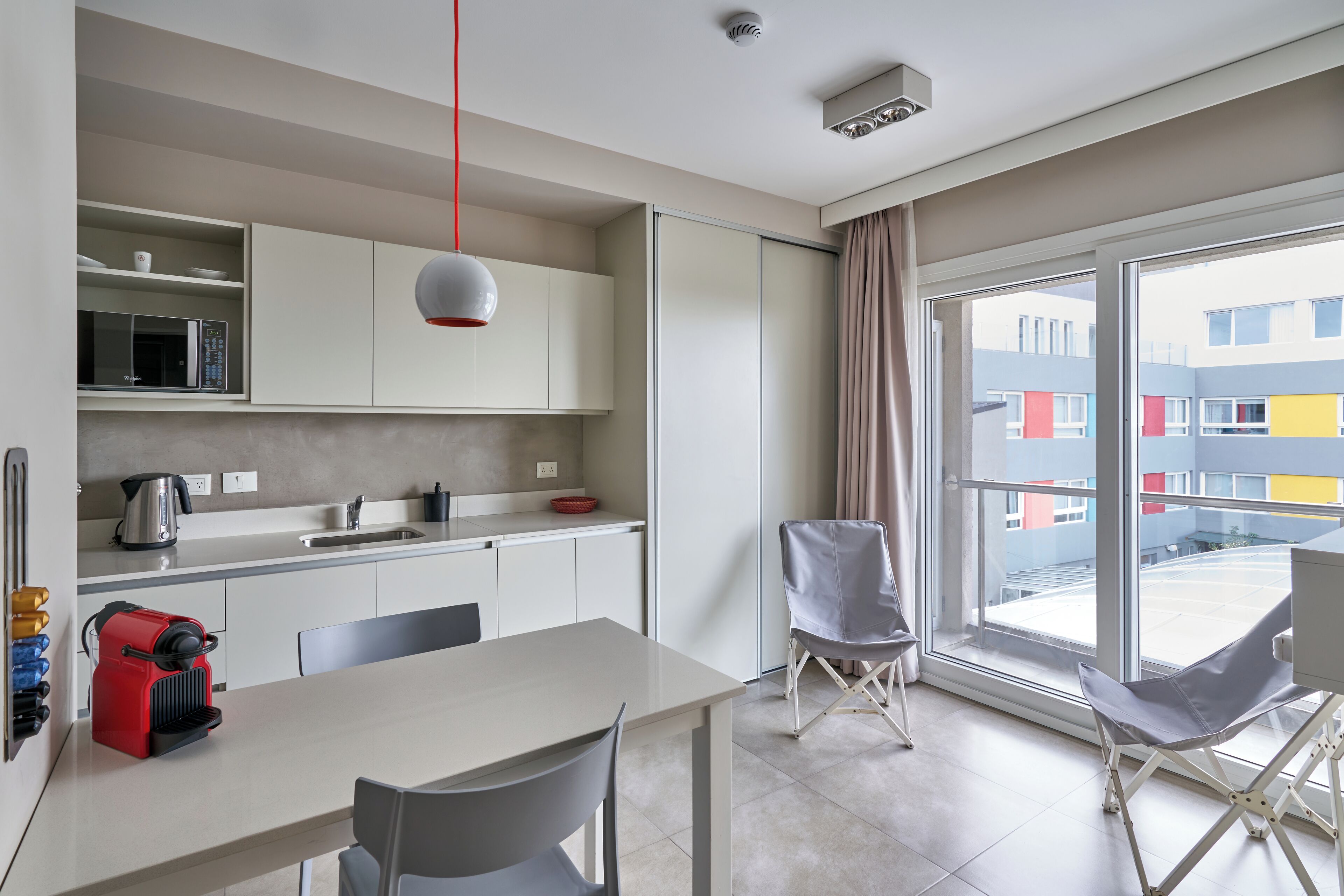 Una cucina moderna con zona pranzo, ampie finestre e vista su edifici colorati.