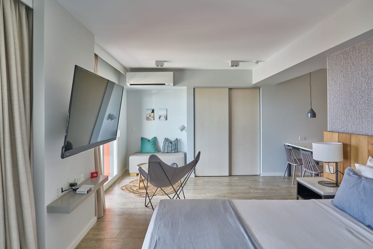 Een moderne hotelkamer met een bed, een bureau, een stoel, een televisie en een kledingkast.