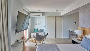 A modern hotel room with a bed, a desk, a chair, a TV, and a wardrobe.