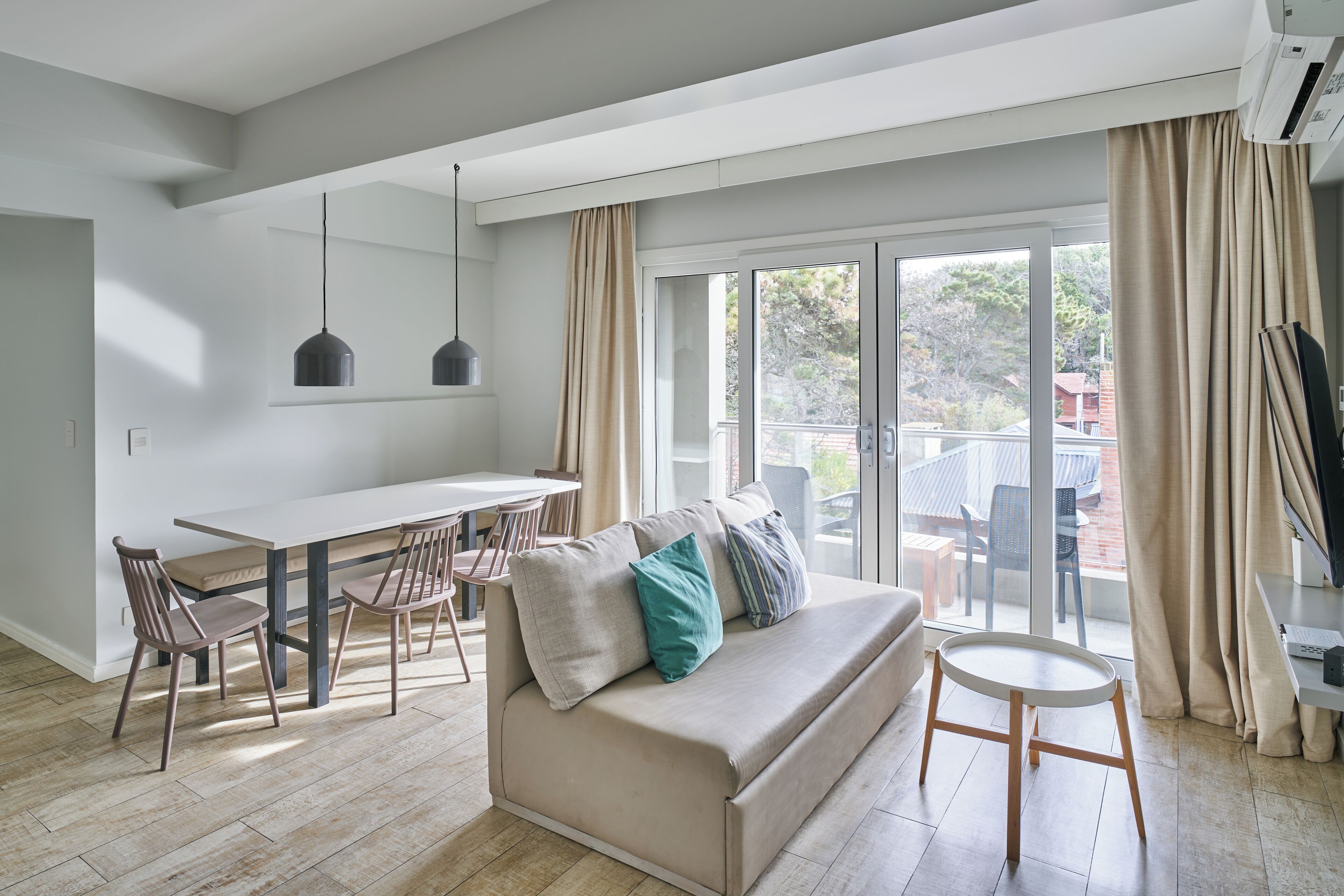 A modern living room with a sofa, dining table, chairs, and a small round table.