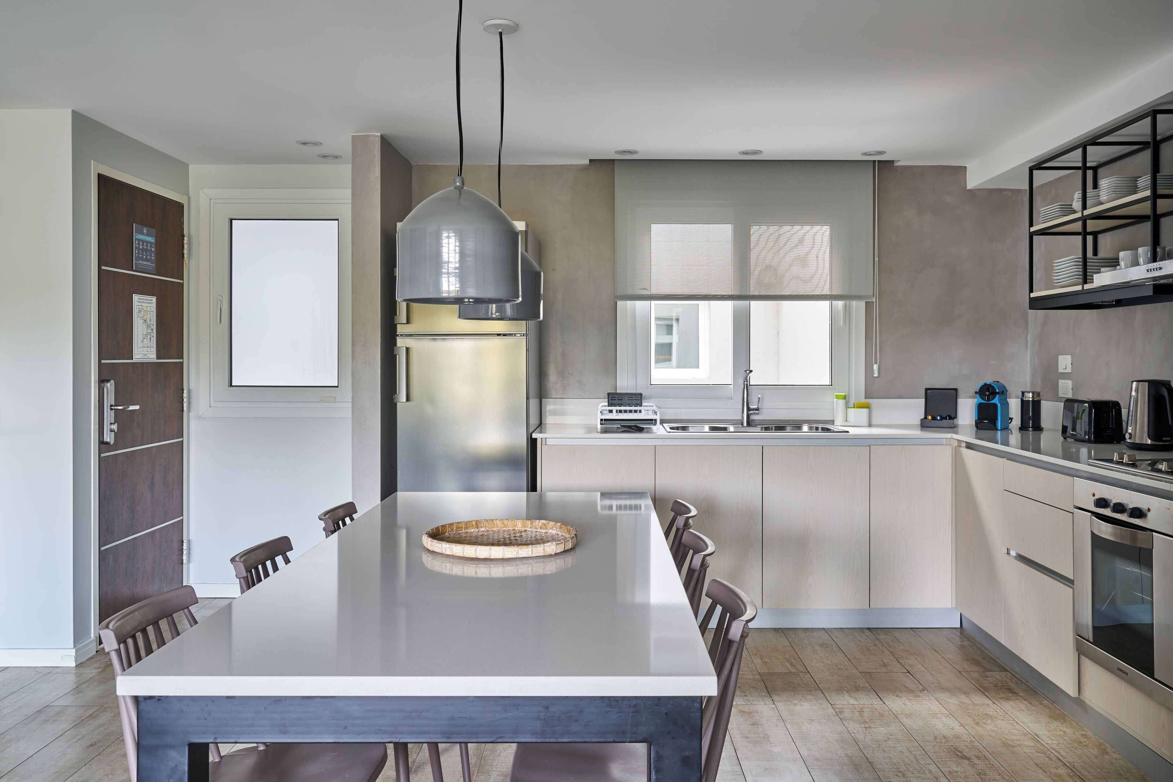 Una cocina moderna con una isla grande, electrodomésticos de acero inoxidable y una lámpara colgante.