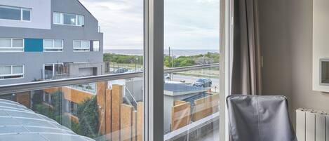 A modern room with a large window, a black chair, and a view of a residential area.