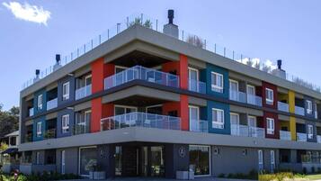 Stylish residential building with modern design, glass railings, and a vibrant facade.