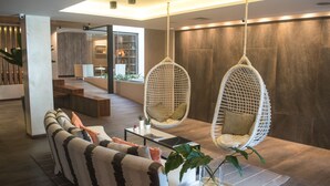 Een moderne woonkamer met een bank, twee hangstoelen, een salontafel en een eethoek.