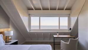 Een slaapkamer met een groot raam, een bed, een bureau en een stoel.