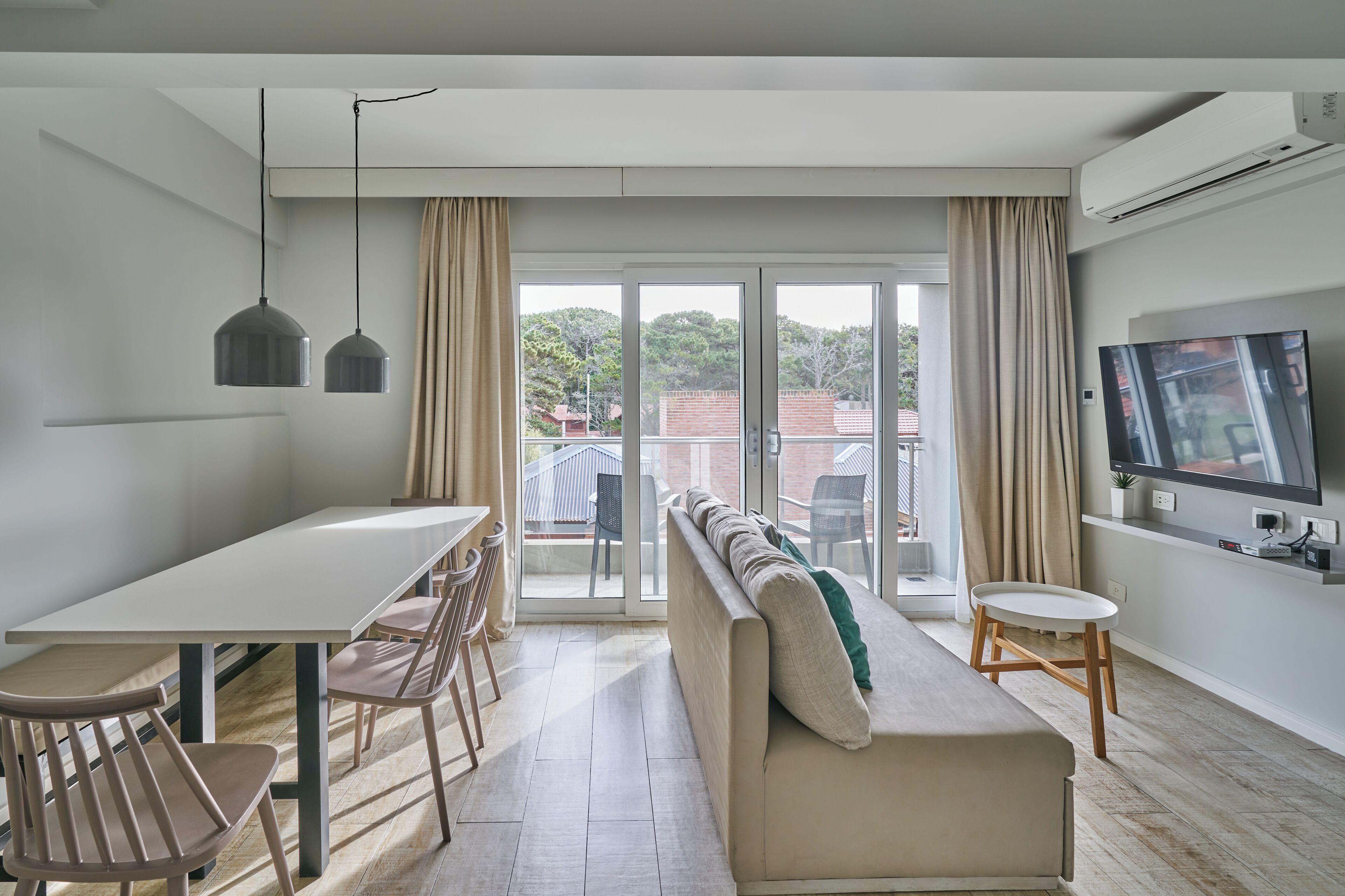 A modern living room with a sofa, dining table, chairs, and a TV.