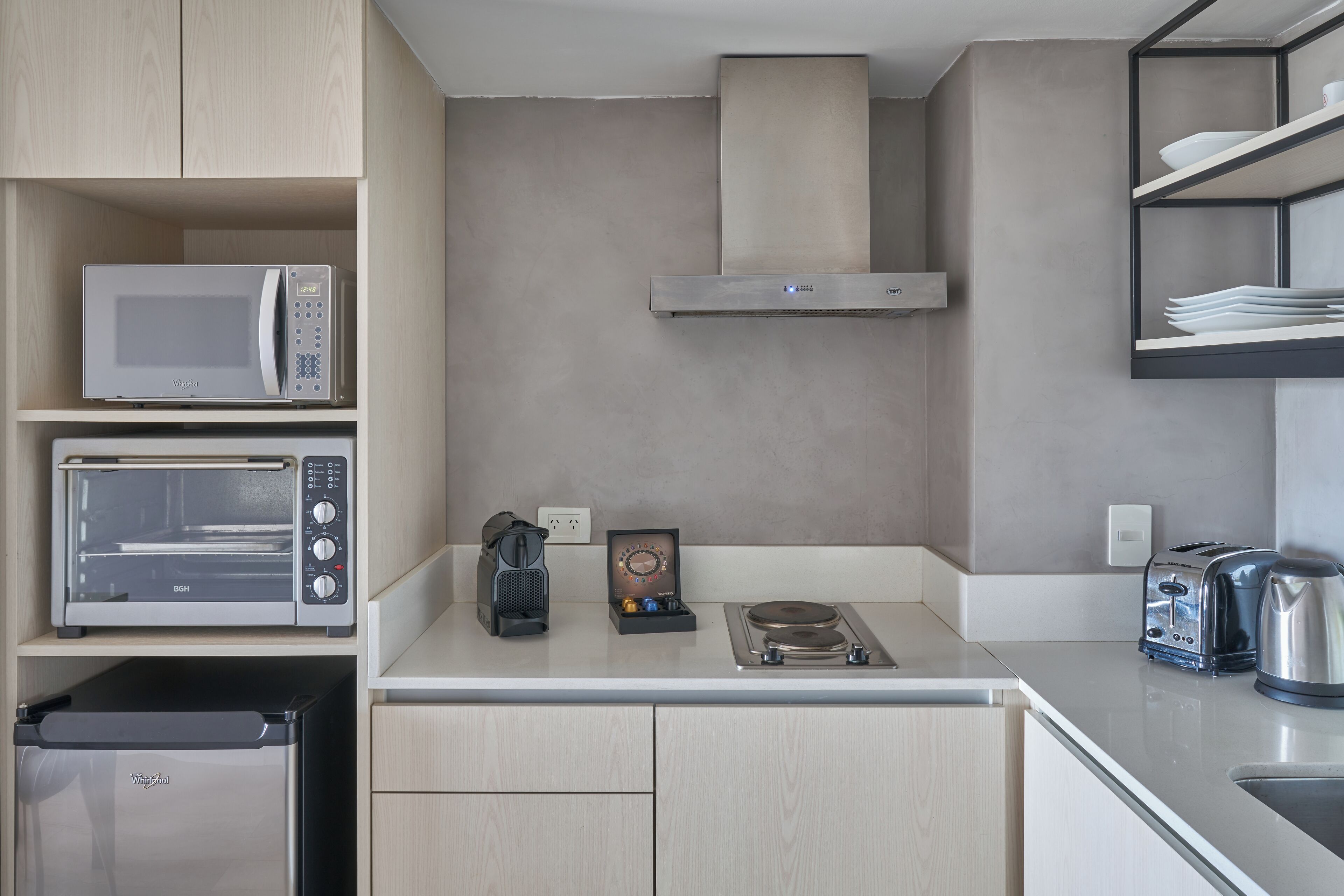 A modern kitchen with a microwave, toaster, coffee maker, and a kettle on the countertop.