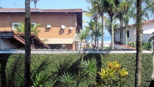 A residential building with a tiled roof, satellite dishes, and a well-maintained garden with various plants.