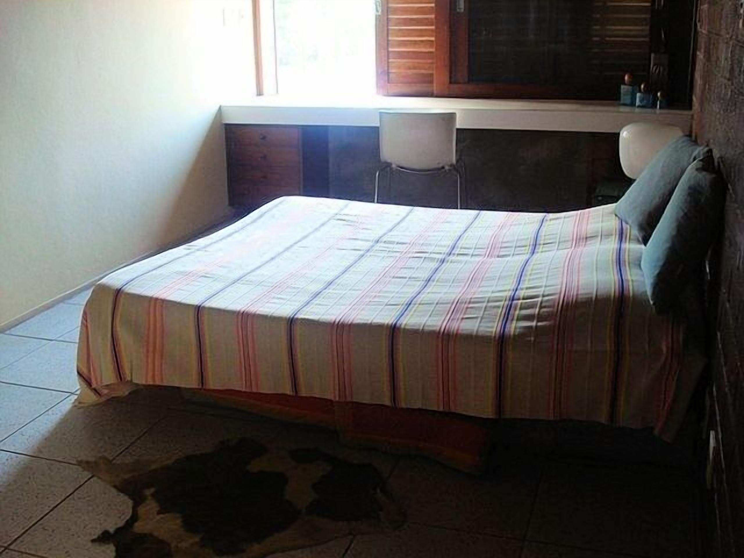 Une chambre à coucher avec un lit, une chaise, une fenêtre et un bureau.
